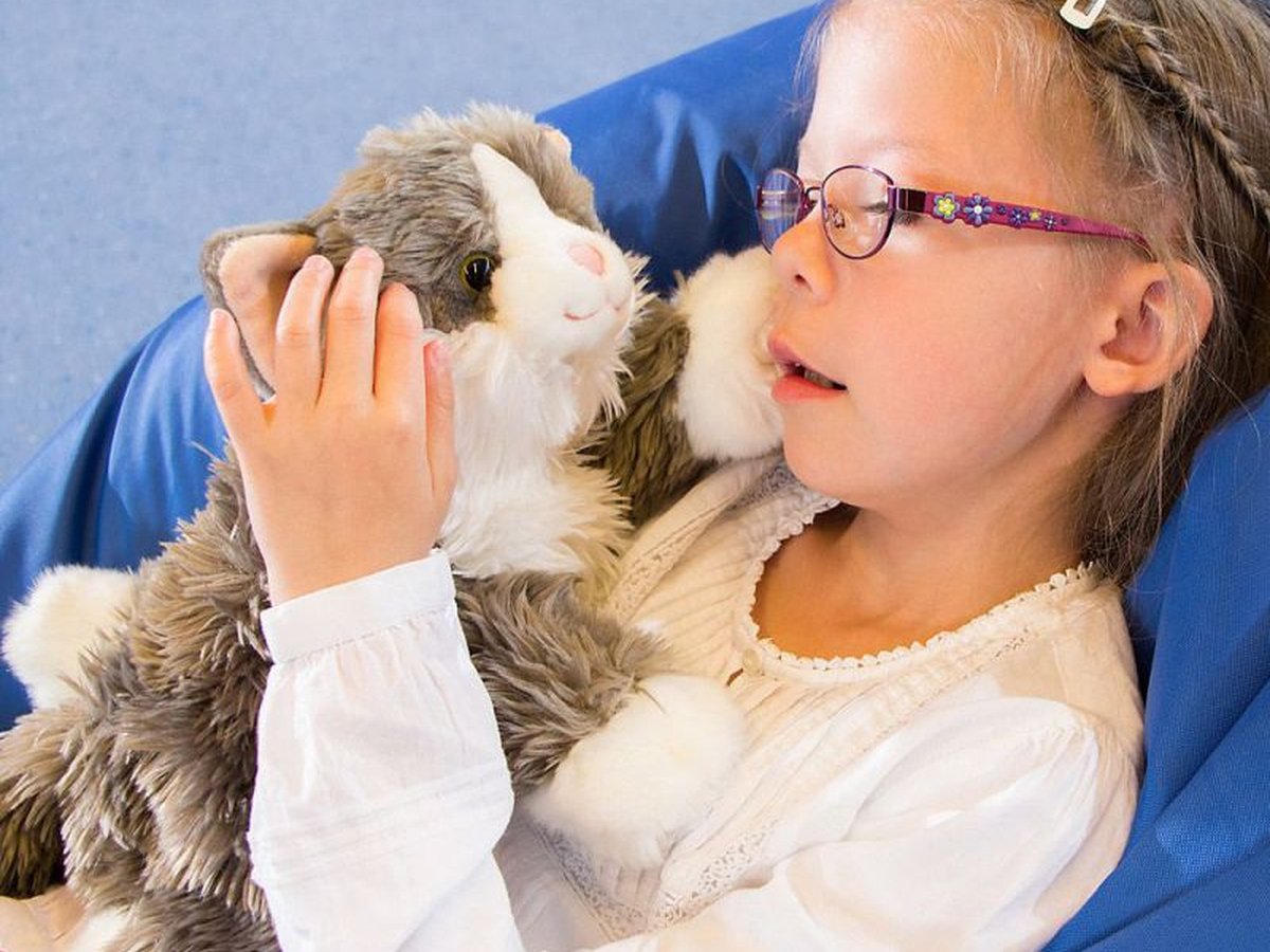 Mädchen umarmt die Joyk-Empathiepuppe Katze Billy